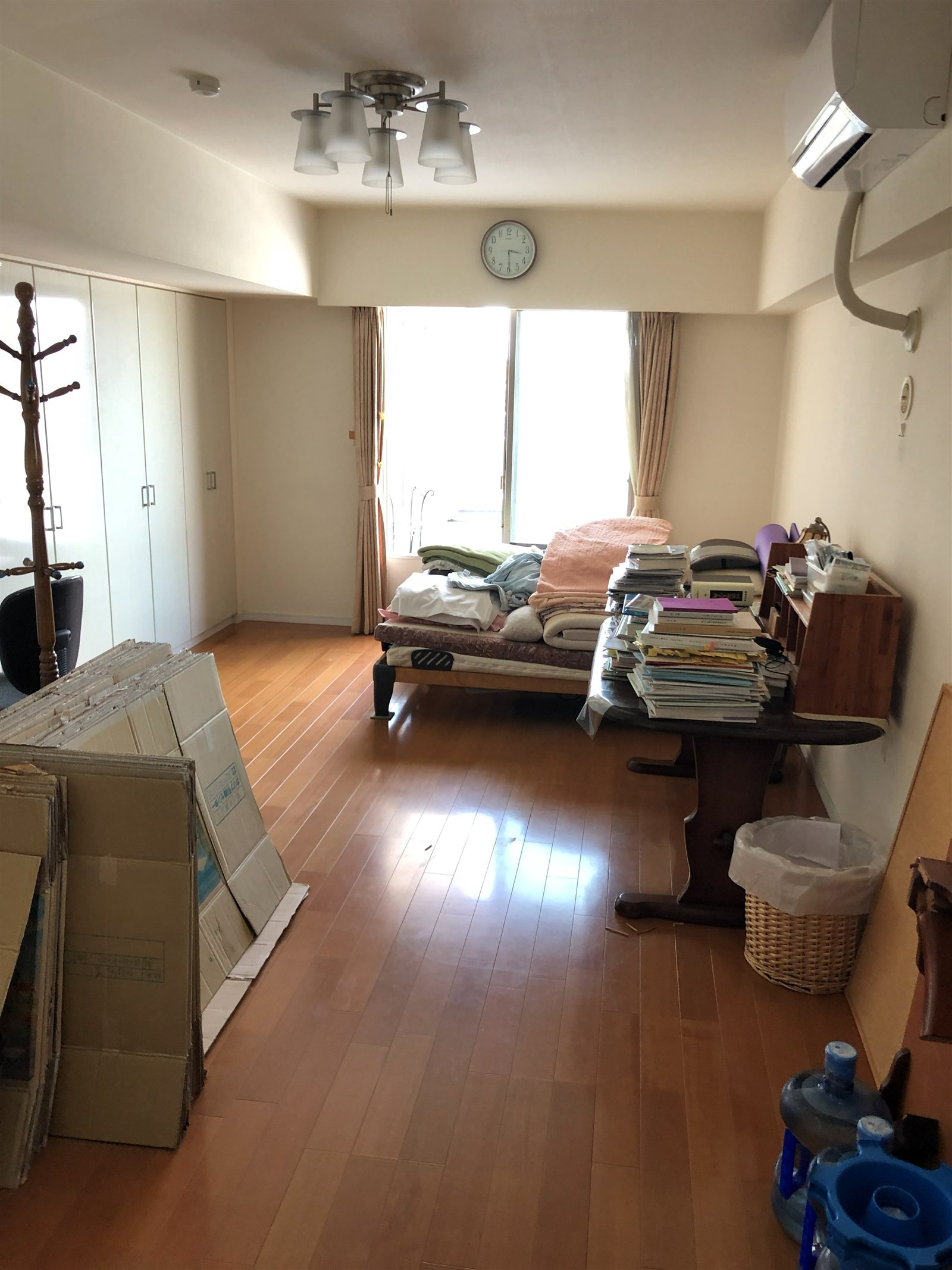 遺品整理前、家具やダンボール、日用品が室内に多く残っている様子